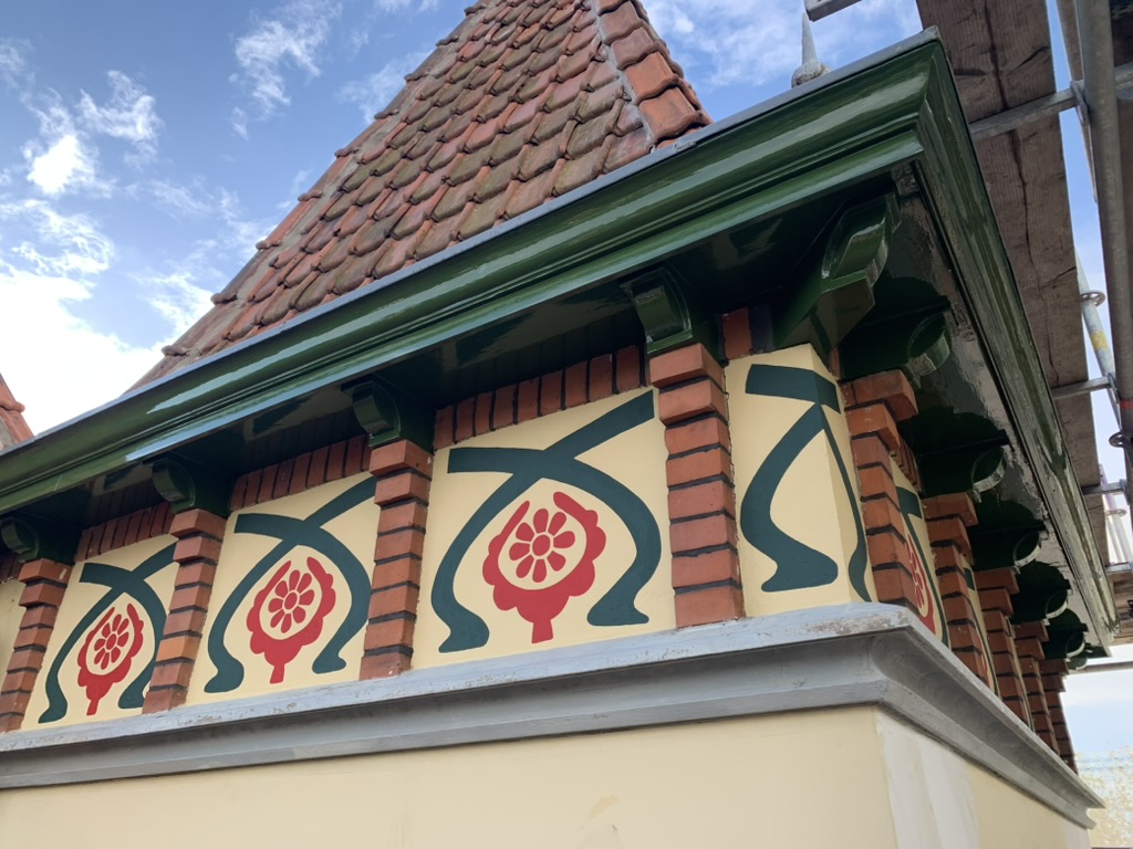 Sierbloem-fries met rode rozetten en groene zweepslagen onder de torenspits
