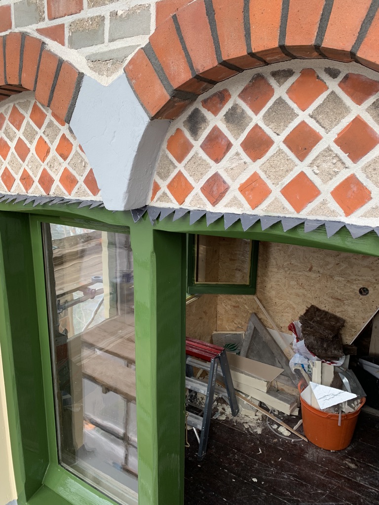 Segmentboog met ruitvormig metselwerk boven een groen kozijn