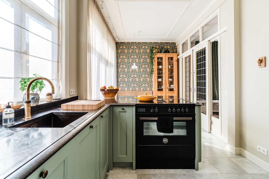 De keuken met marmer, groen paneelwerk en behang in stijl